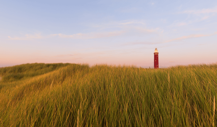 Beautiful Shot Grassy Field With Red Lighthouse Distance Blue Sky